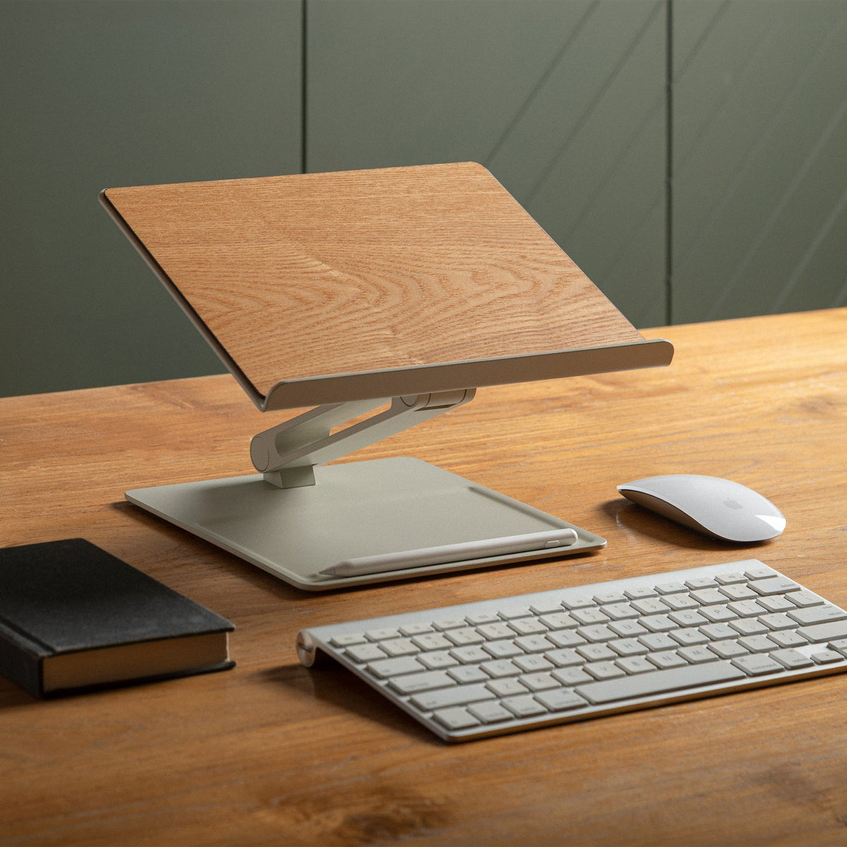 Sandstone and ash stand raised on a wood desk with a keyboard, mouse and notebook beside it