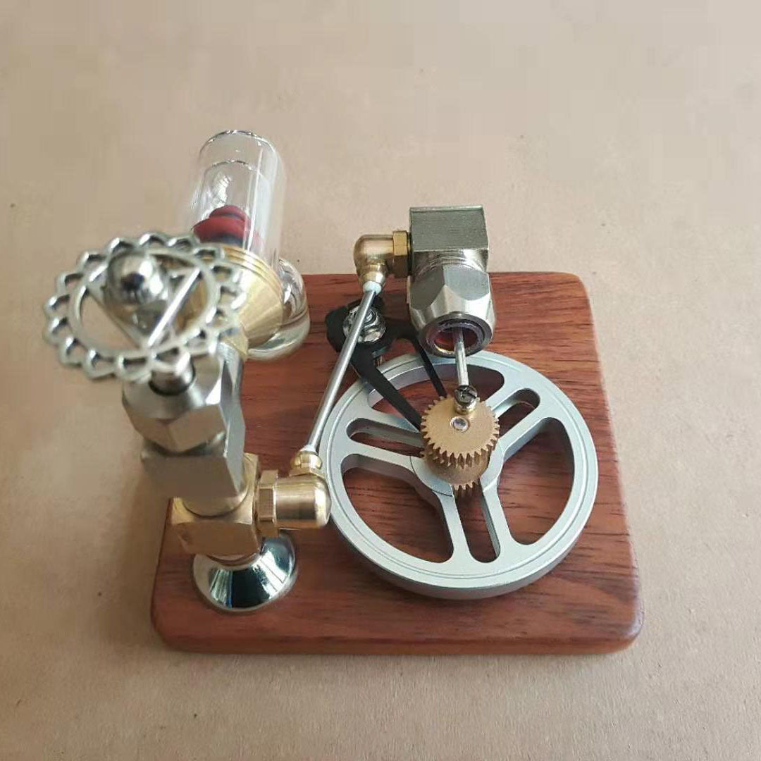 Stirling engine model with a silver flywheel and gold gear on a dark wooden base