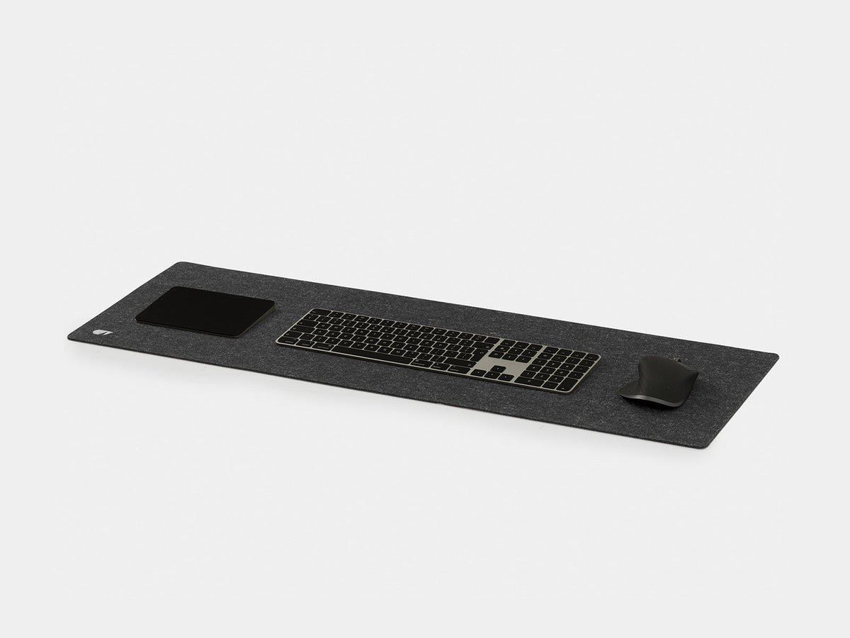 Anthracite felt desk mat at an angle with a keyboard, trackpad and mouse