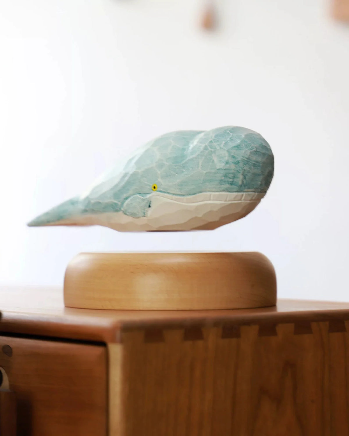 The floating whale from a front corner, the carved facets of its blue back catching the light.