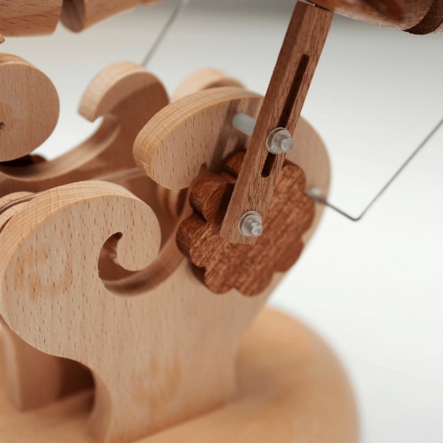 The slotted arm and the wire that lift the pair, over the carved waves.