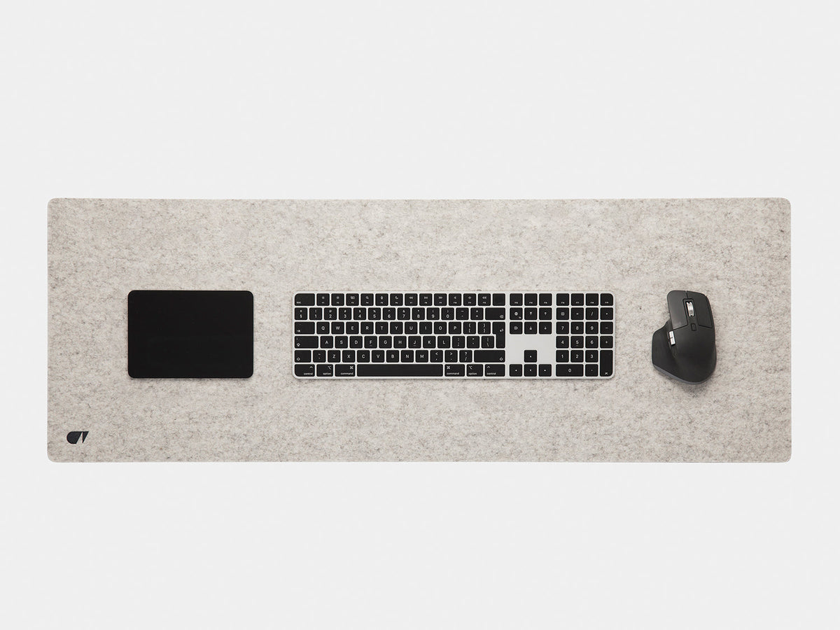 Stone grey felt desk mat from above with a keyboard, trackpad and mouse