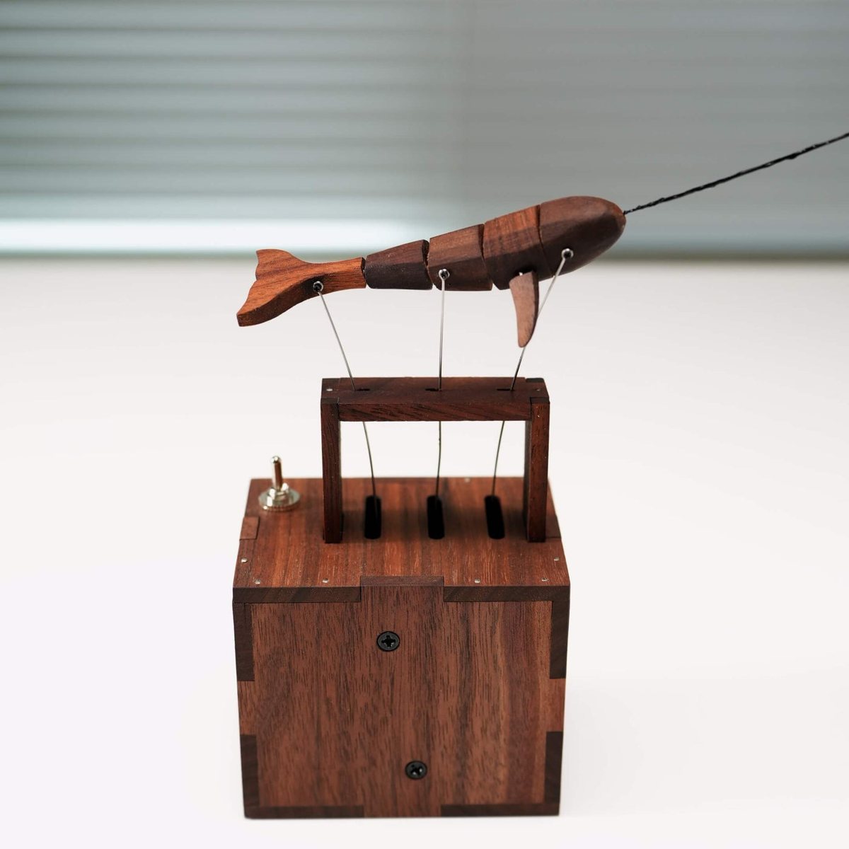 Narwhal on its dark wood box in a white studio, a small switch on the box lid.