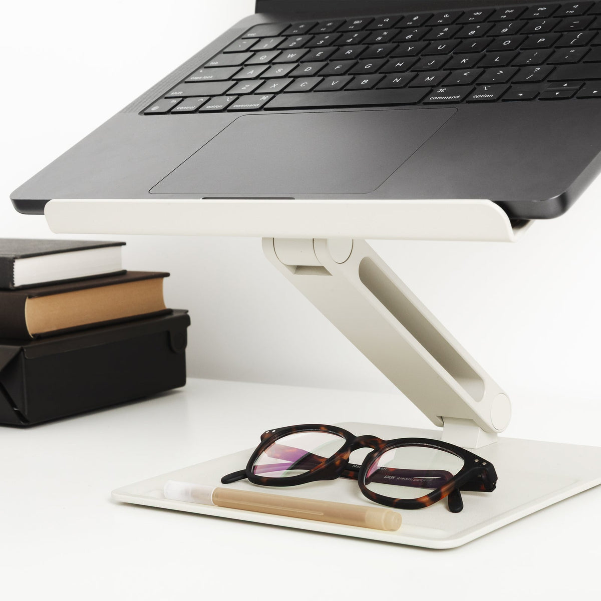 Sandstone stand holding a laptop at a raised angle, with glasses and a pen on the base tray