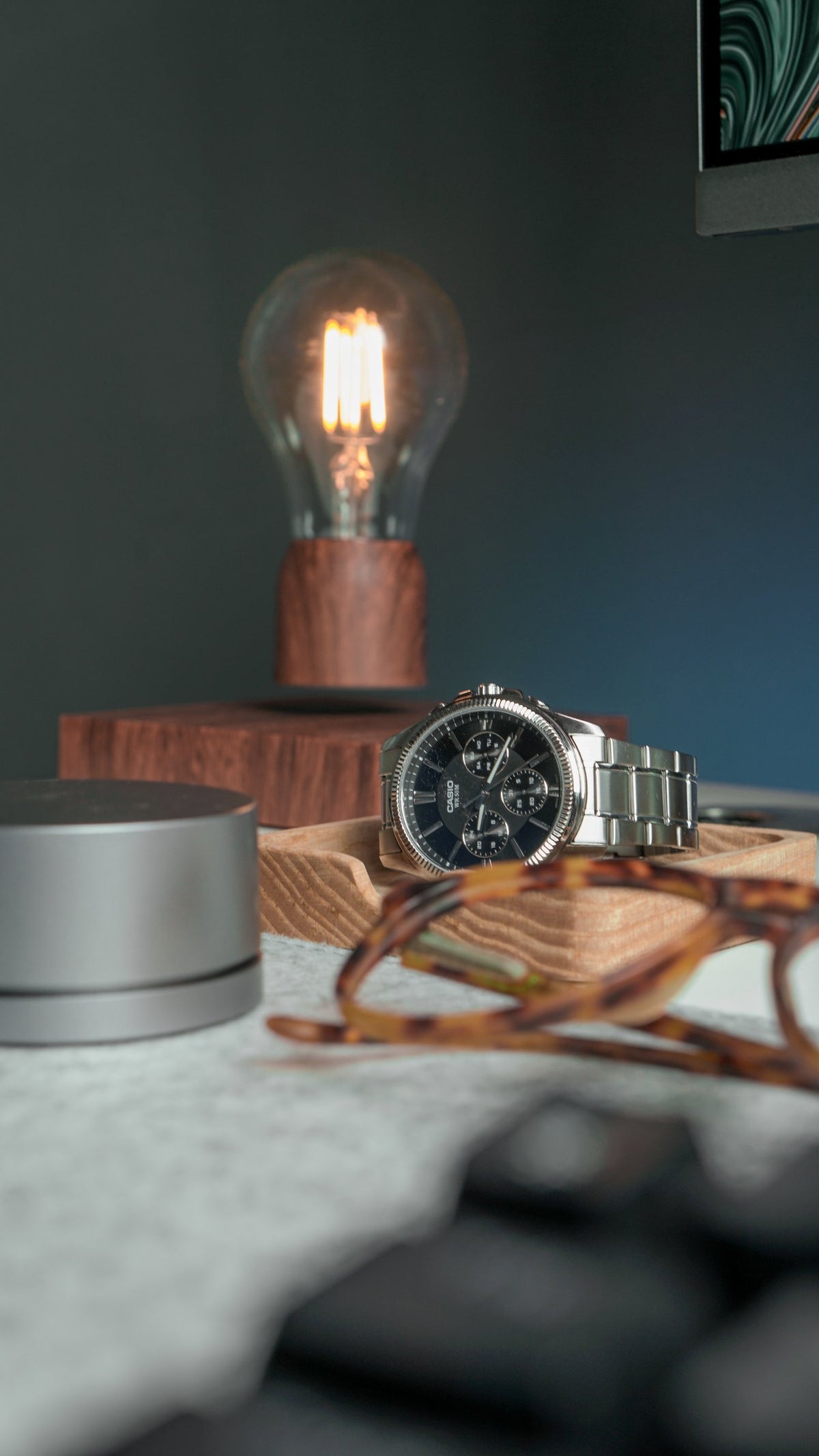 Levitating bulb lamp, watch and glasses on a desk