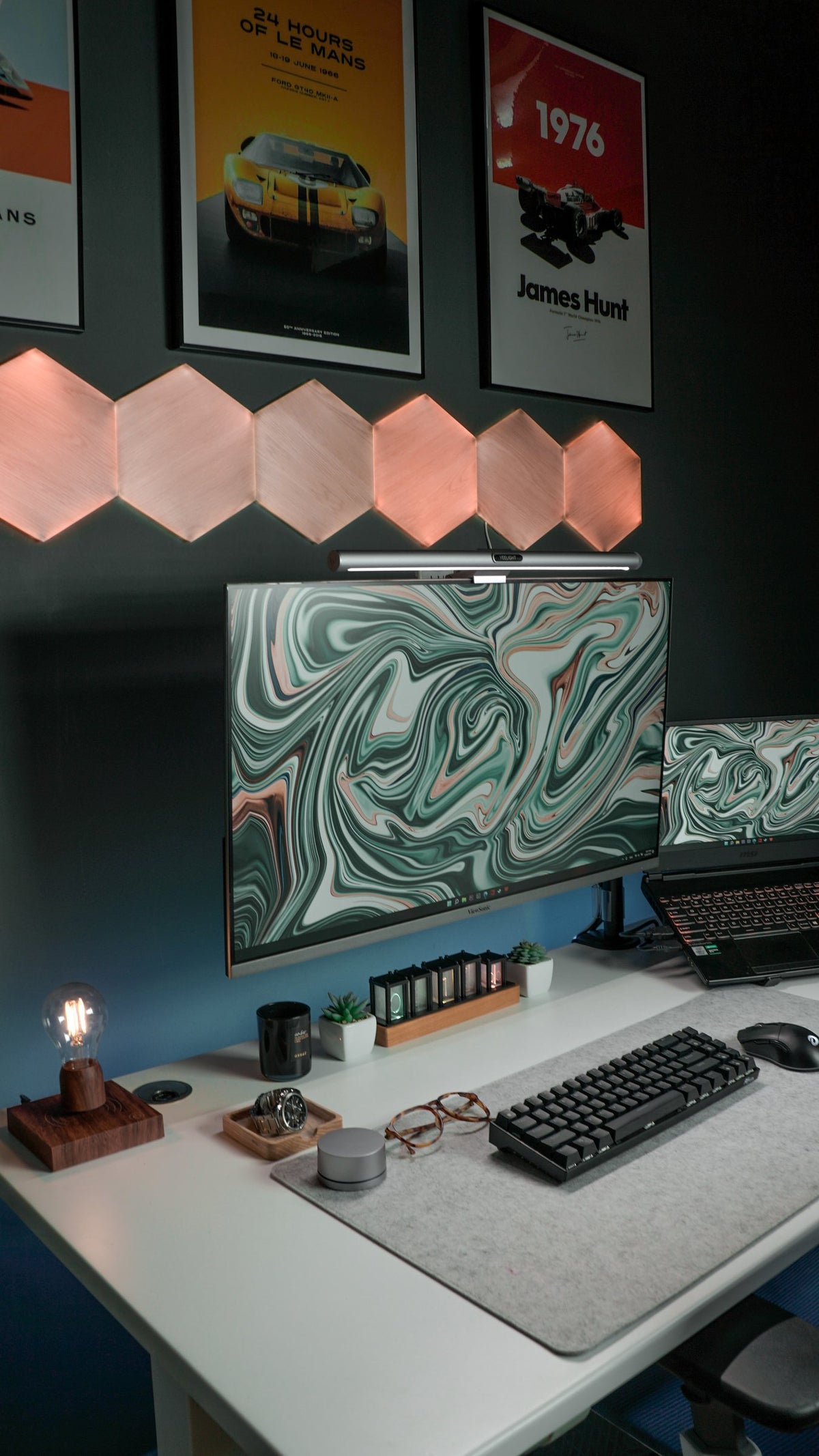 Vertical view of a white desk with green marble monitor, racing posters and hexagon lights