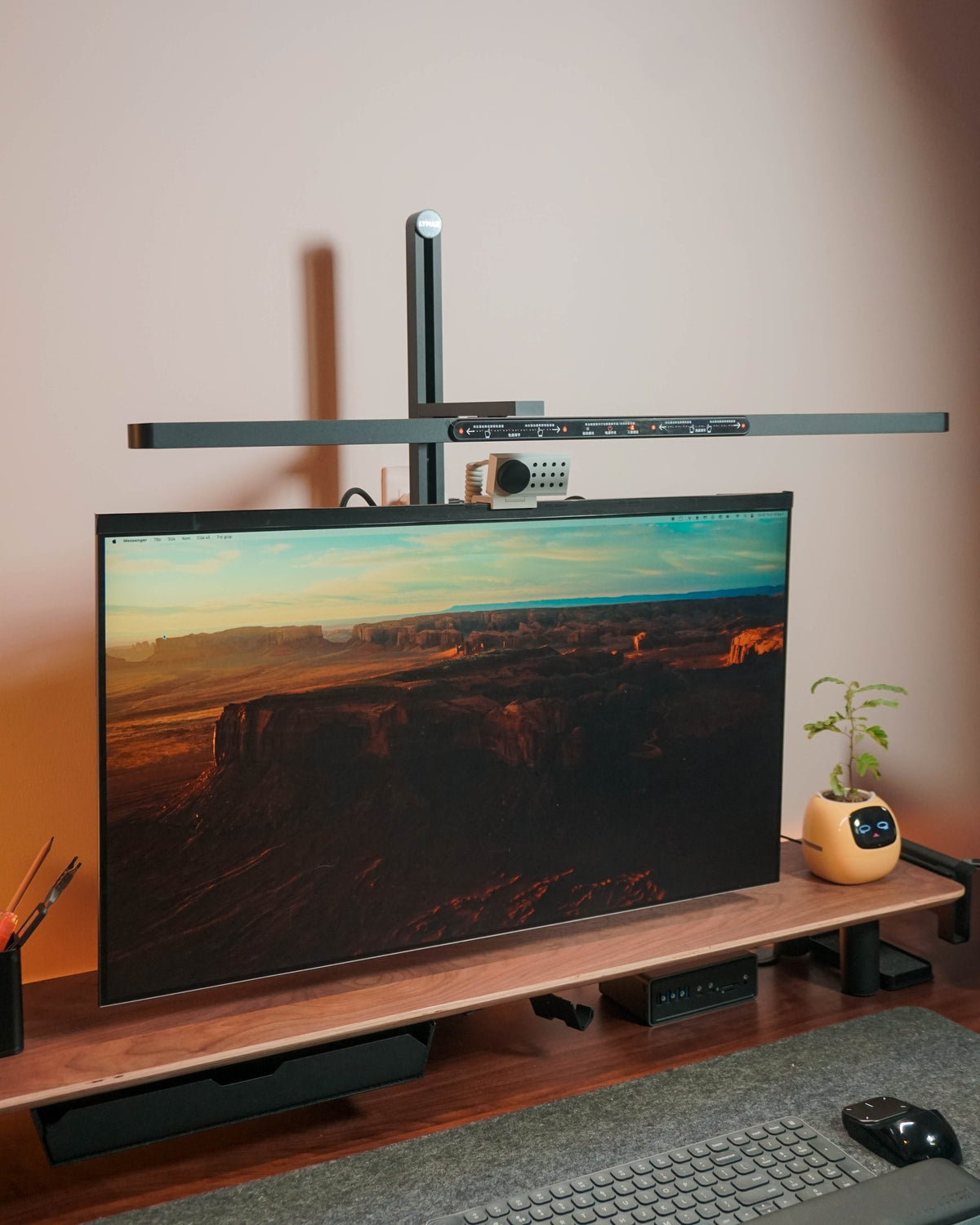 Monitor on a walnut shelf under an arm-mounted light bar