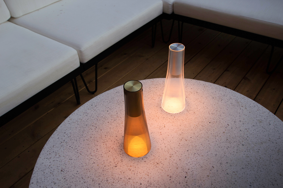 A smoke and a clear Candel lamp lit on a stone table beside a lounge seat
