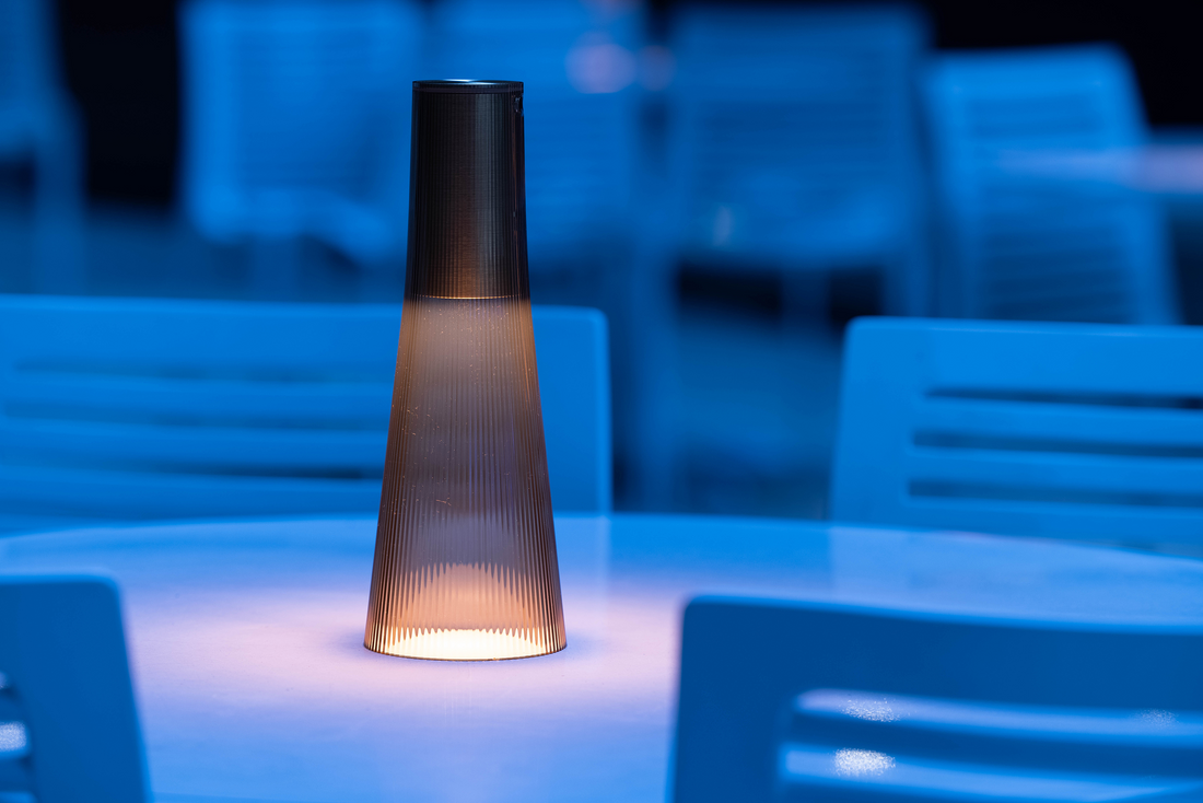 A smoke Candel lamp lit on a table with blue light behind