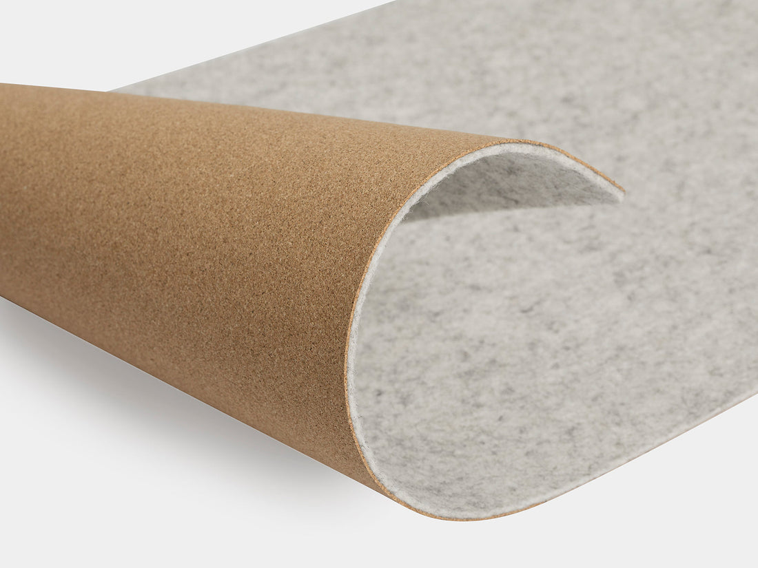 Rolled corner of the light grey felt mat showing the cork base underneath