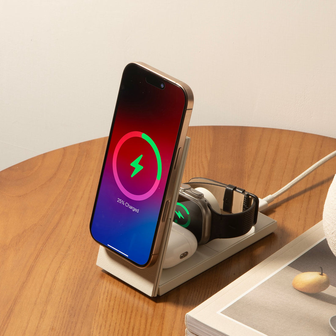 Sandstone charger on a wooden table holding a phone, earbuds and a watch