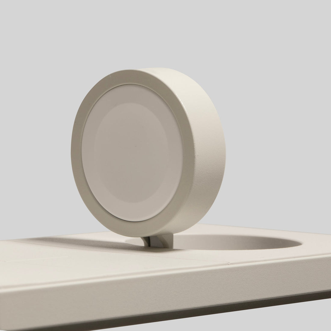 Close-up of the round watch charging puck in a curved cutout on the sandstone base