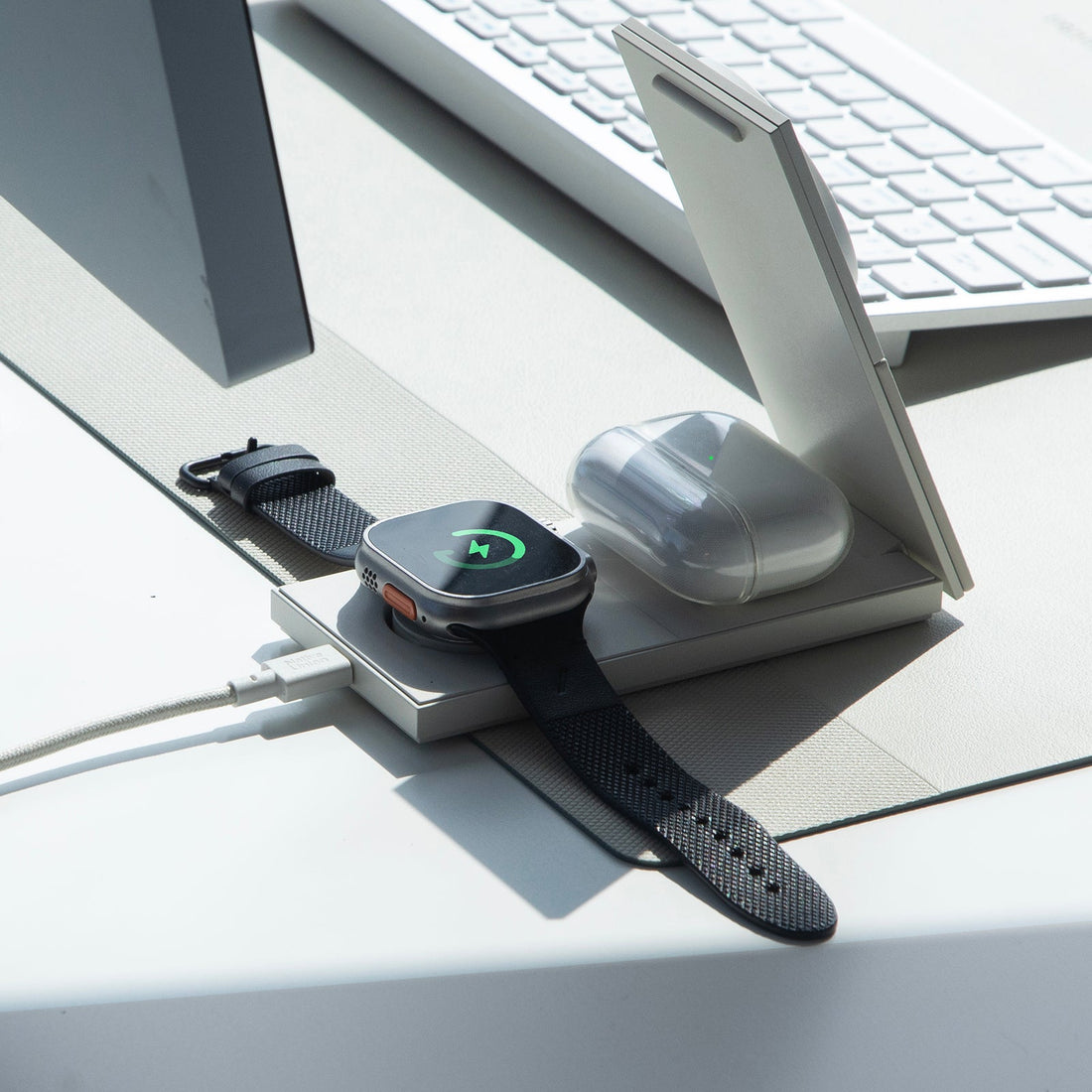 Folded sandstone charger on a desk near a keyboard, with a watch and an earbuds case on the base