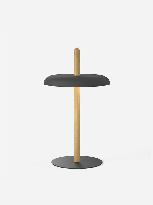 The Nivel table lamp with a black shade on a light oak post and a black steel base