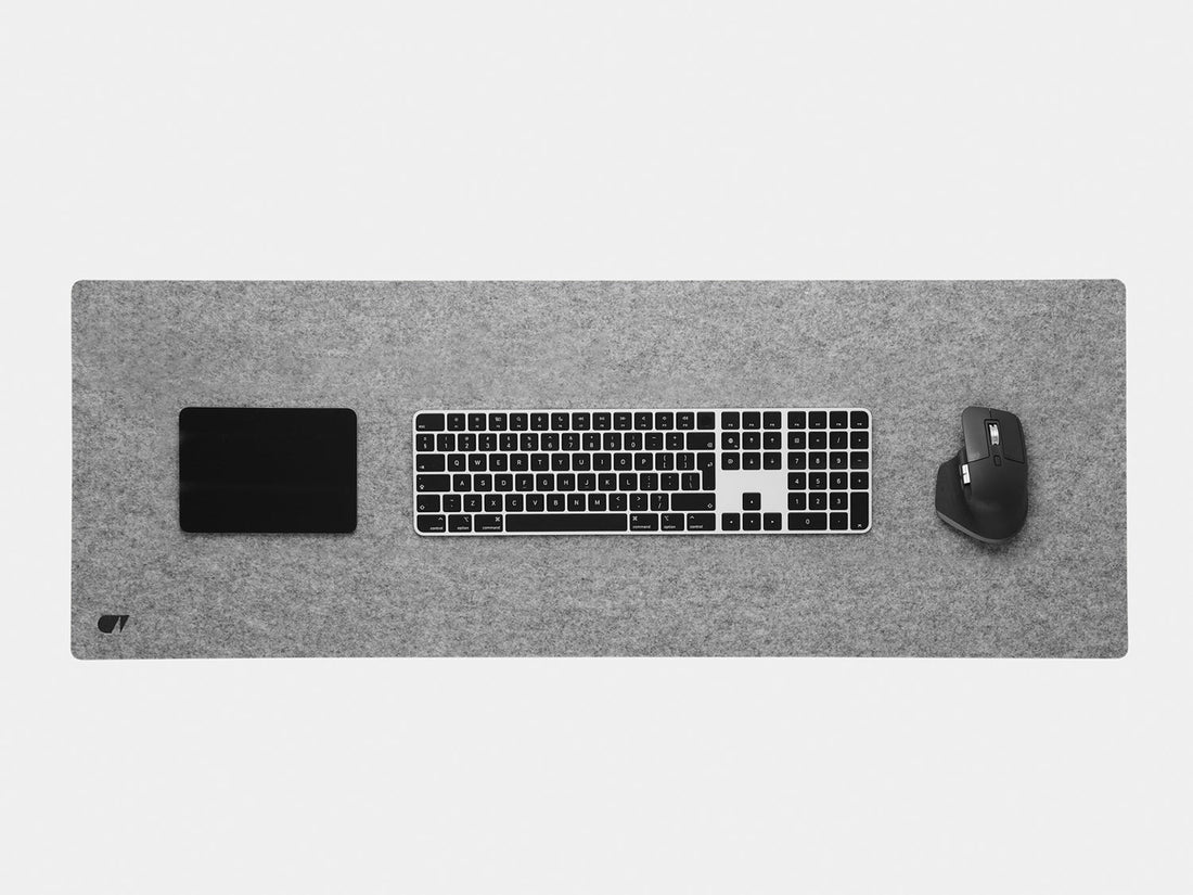Grey felt desk mat from above with a keyboard, trackpad and mouse
