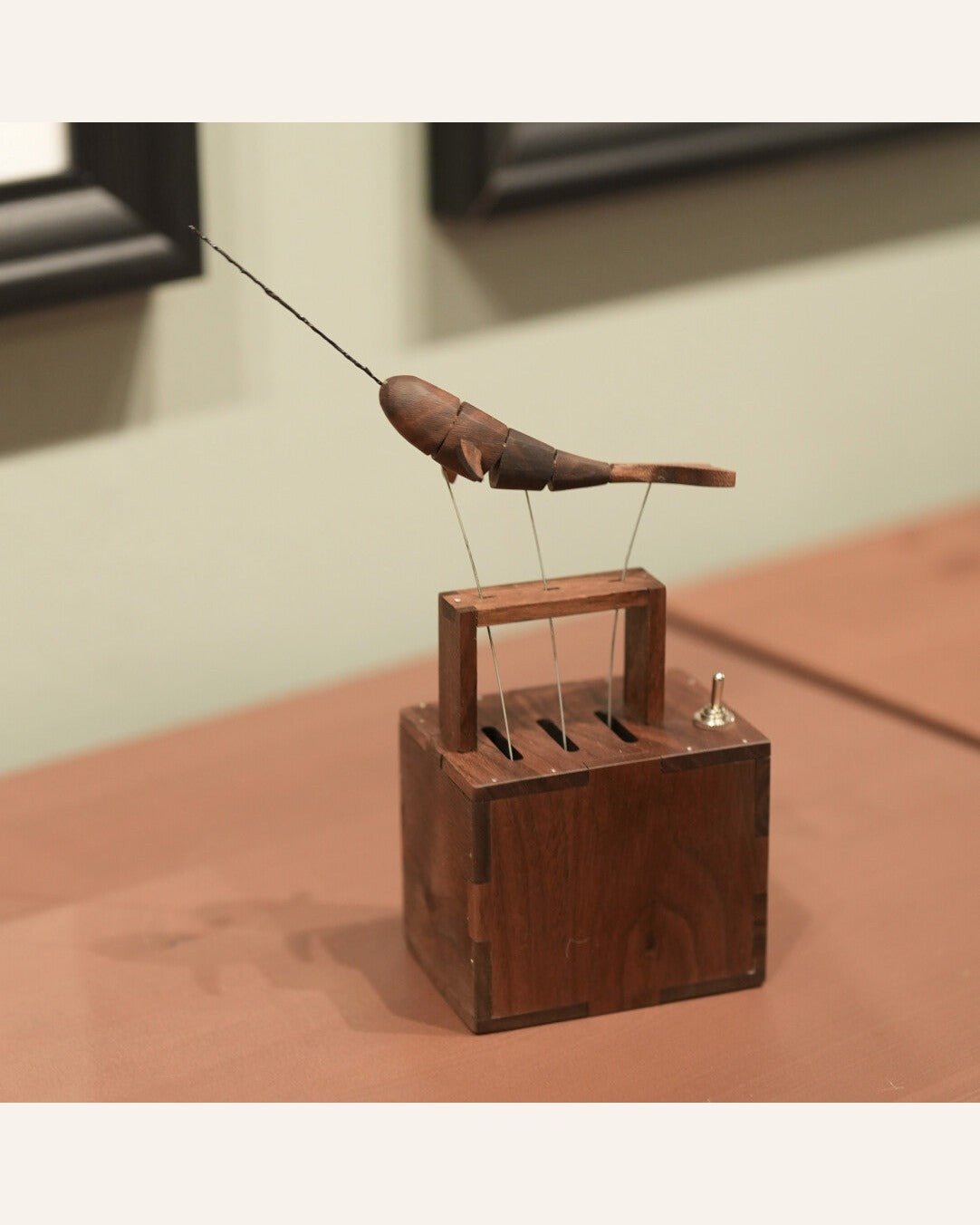 Narwhal with its full tusk above the wood box with a small switch, on a pink-brown table.