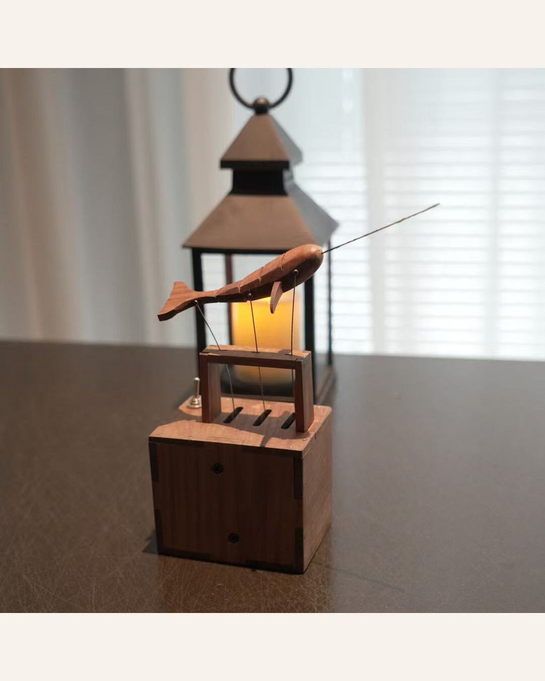 Narwhal automaton on its box in front of a lantern with a glowing candle.