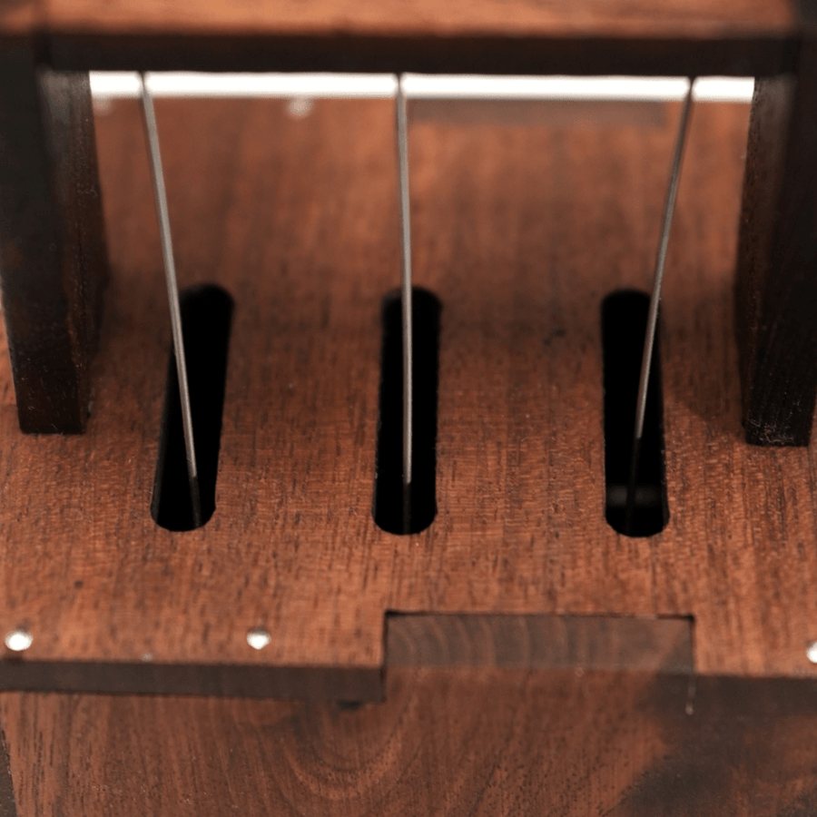 Three thin wires rising through slots in the dark wood box.