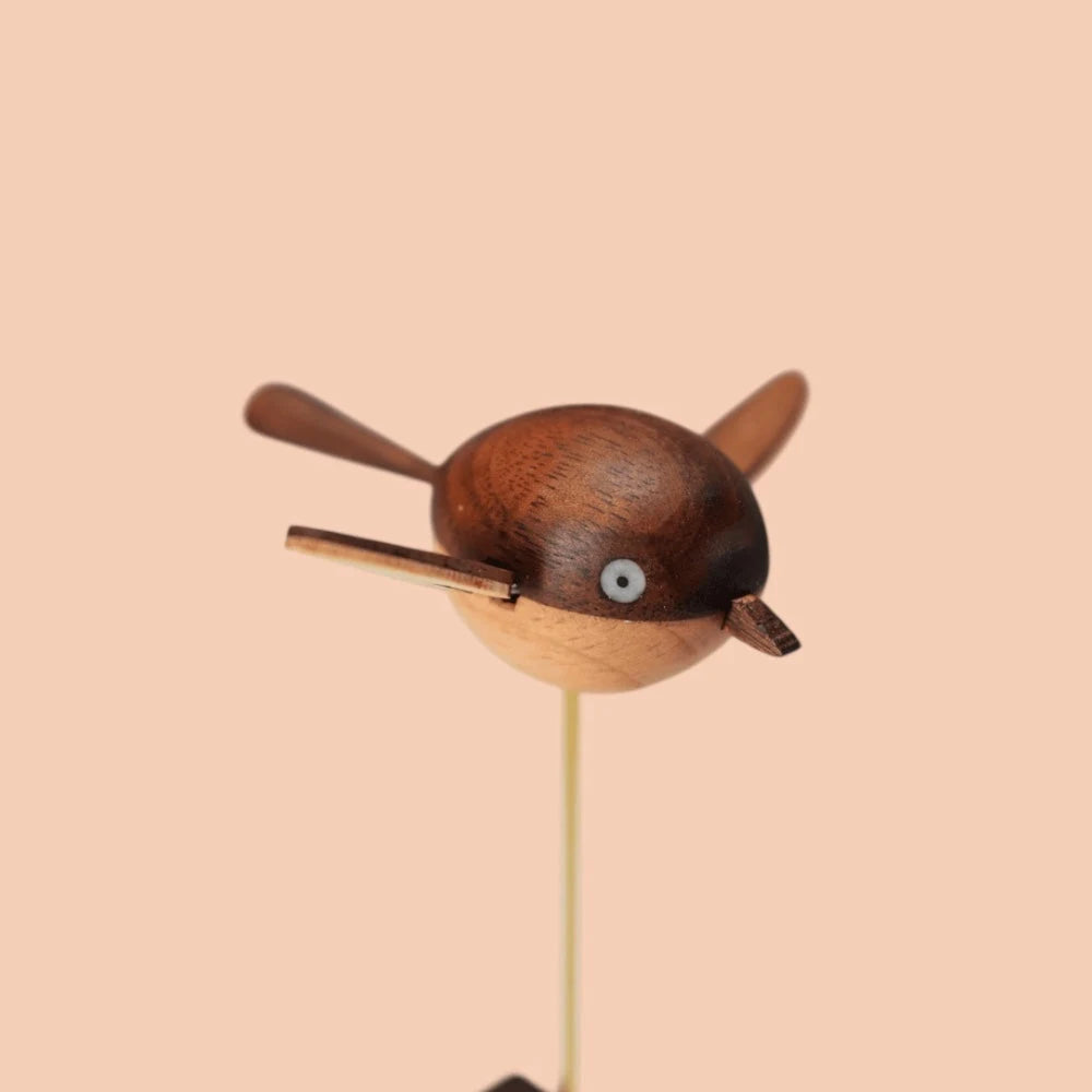 Three-quarter view of the bird with its wings raised, the brass rod below.