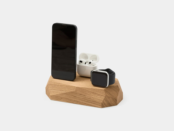 Oak faceted dock holding a phone, an earbuds case and a watch